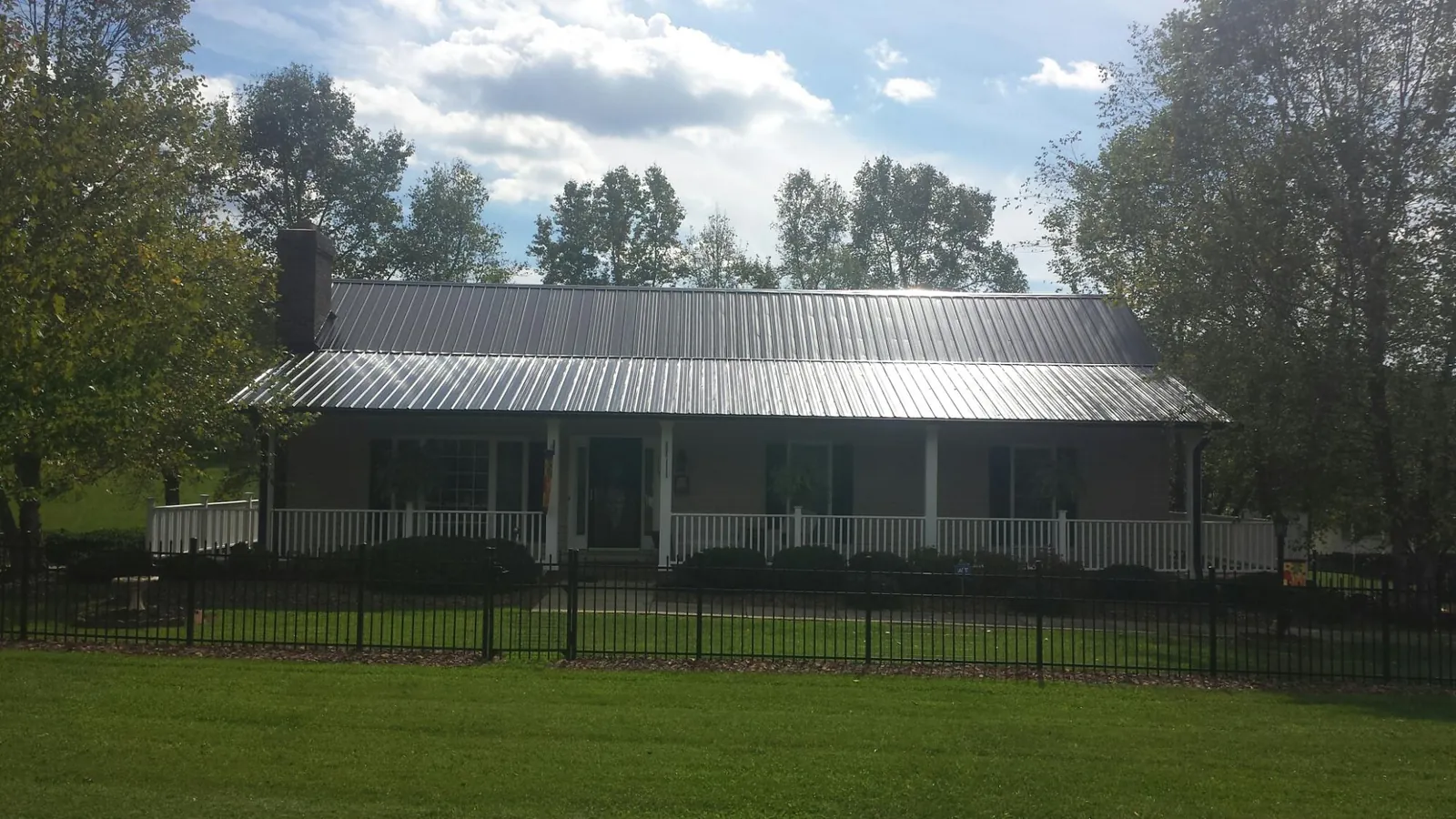 Gray metal roof on a brick ranch with a full width front porch — Gutter Guard Installation work by our crew in Shirley