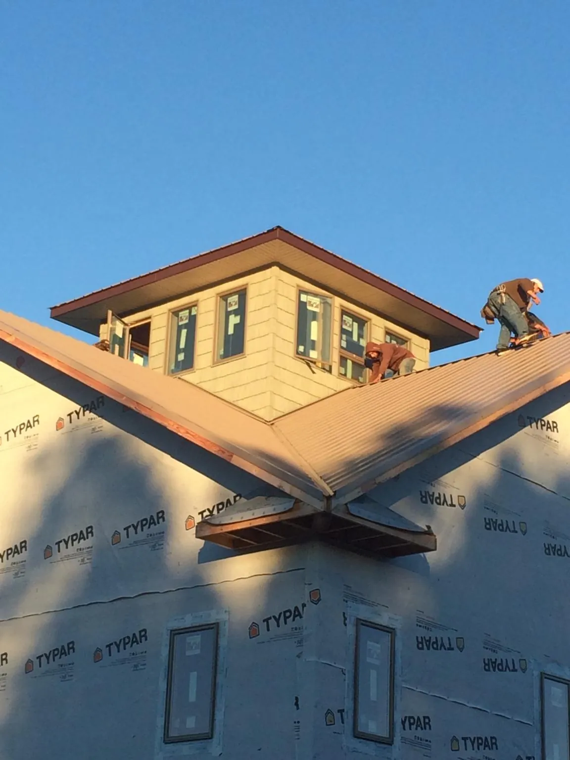 Roofers working around a rooftop cupola on a new metal roof at sunset — Roof Waterproofing in Shirley by Roofing Brothers